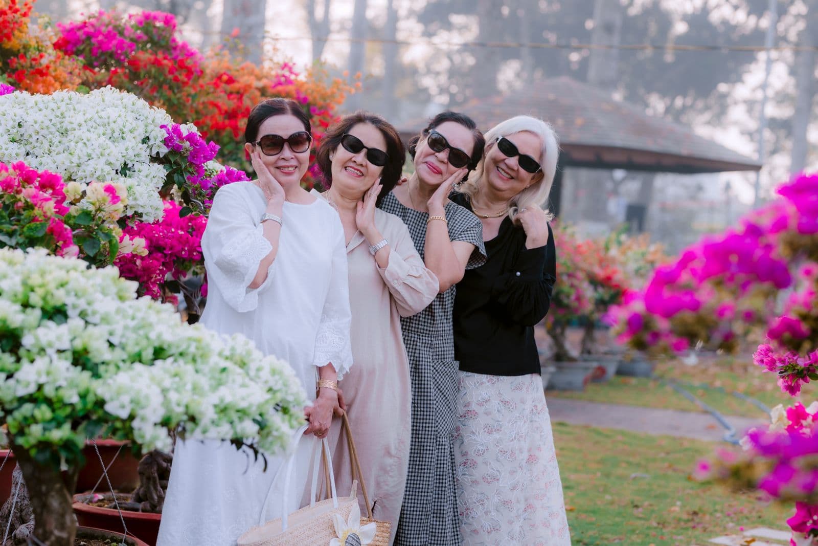 กลุ่มหญิงสูงอายุชาวไทยยิ้มแย้มเพลิดเพลินในสวนดอกไม้ด้วยกัน