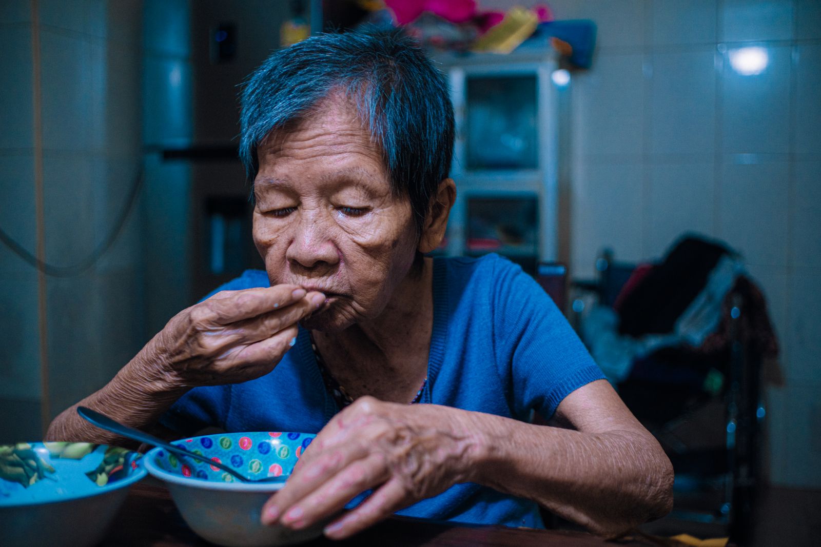 An older Thai woman eating a meal at home