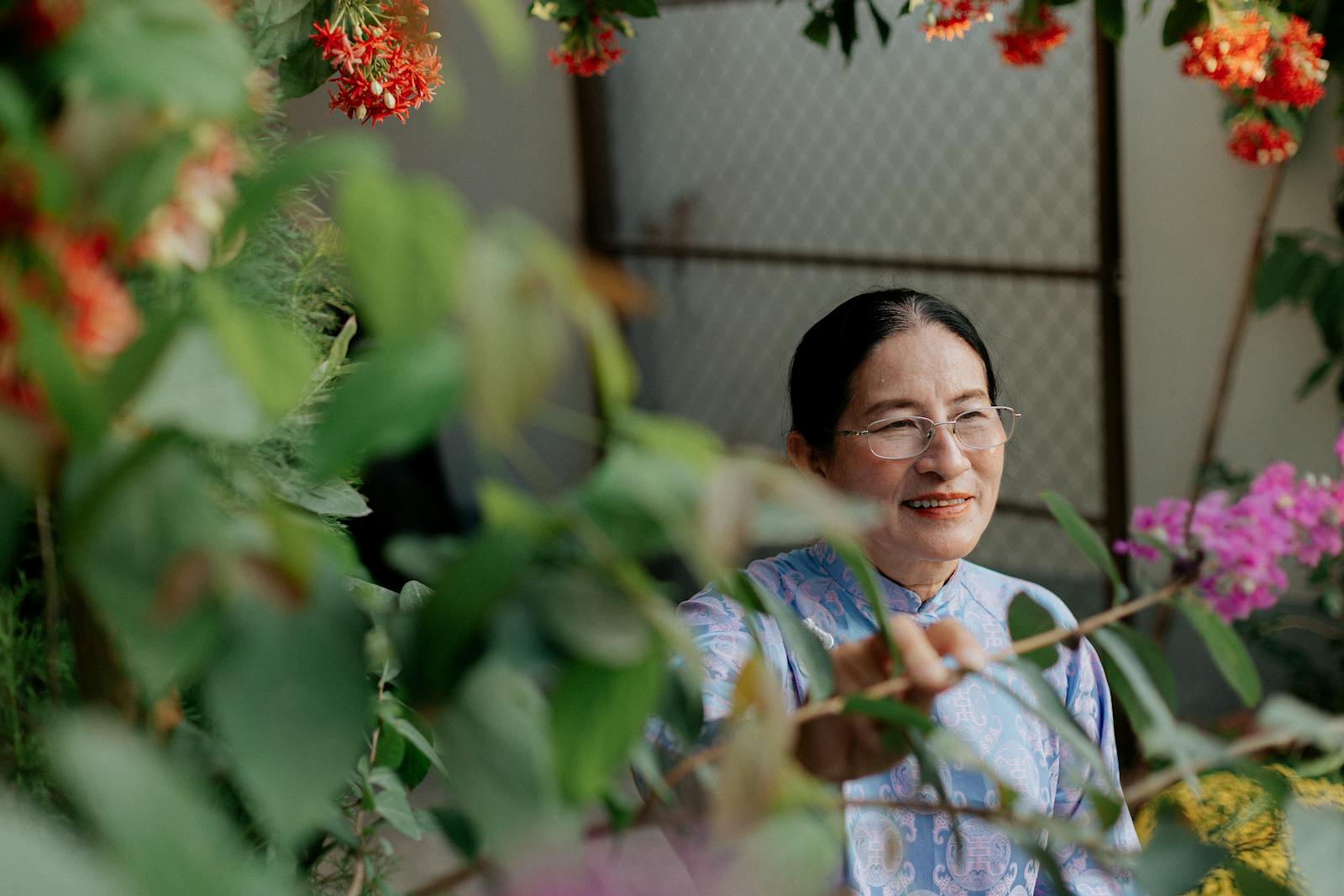 ผู้สูงอายุหญิงไทยดูแลต้นไม้ในสวนที่มีแสงแดดส่อง